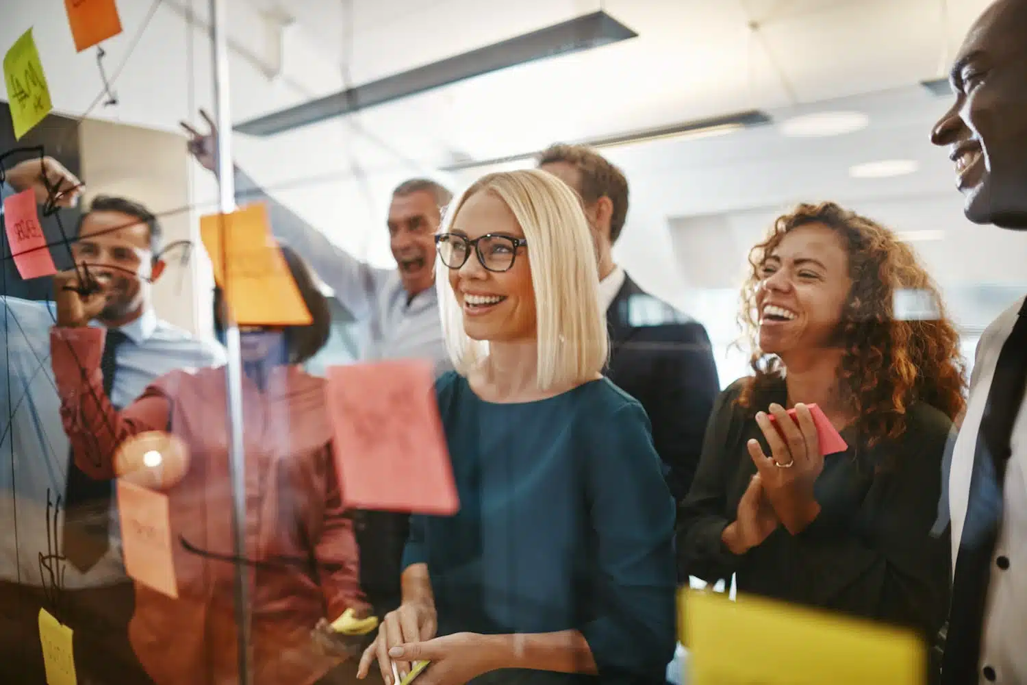 Diverse businesspeople brainstorming with notes on a glass wall
